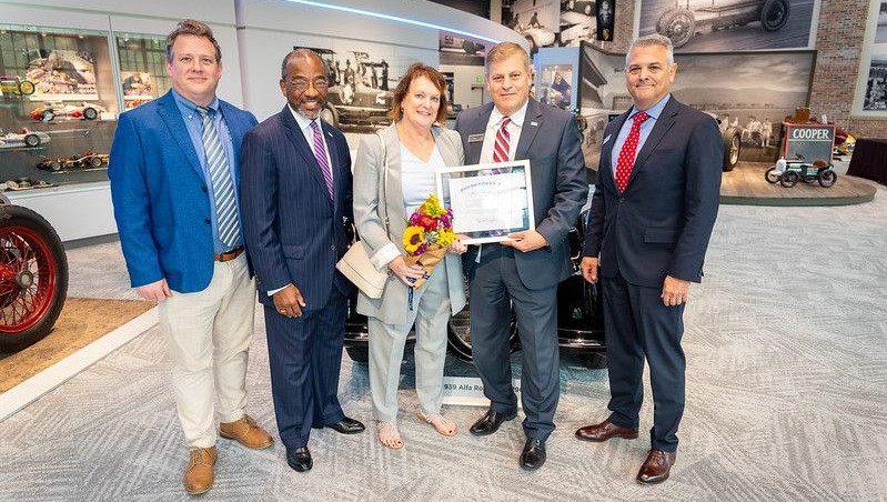 Men and woman standing with man holding document