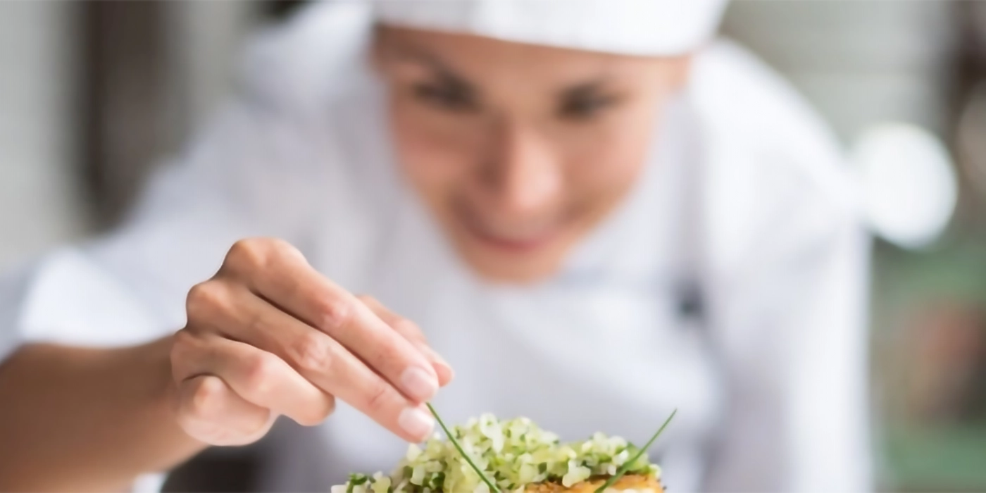 A chef adding garnish to food