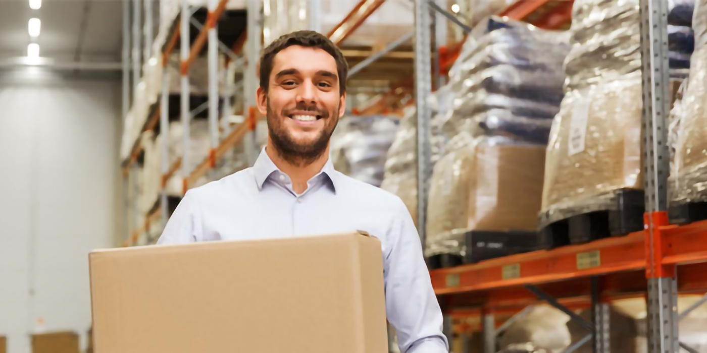 A a man holding a cardboard box in a large warehouse