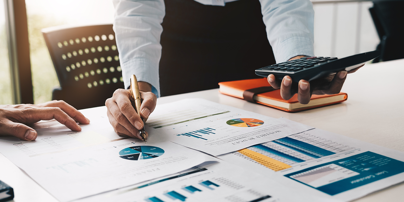 Closeup of a hand writing on a series of printed charts