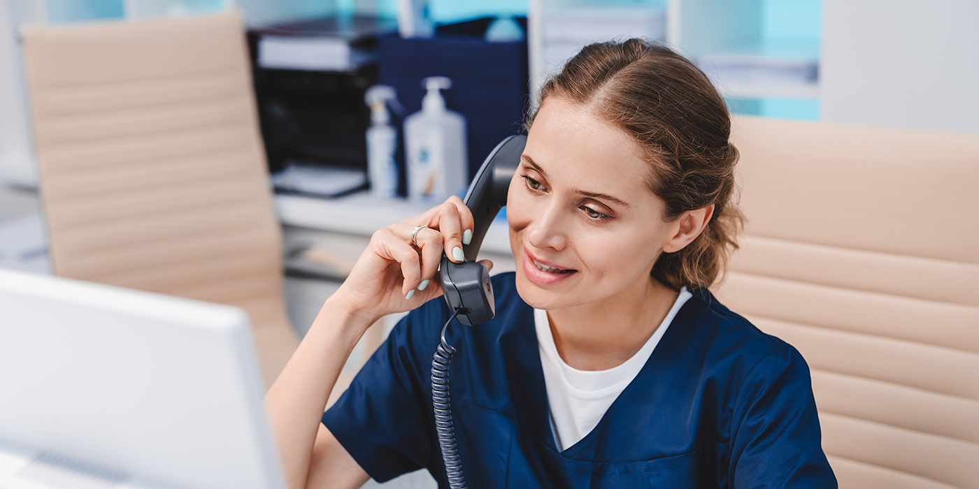 A woman in medical scrubs talking on the phone.