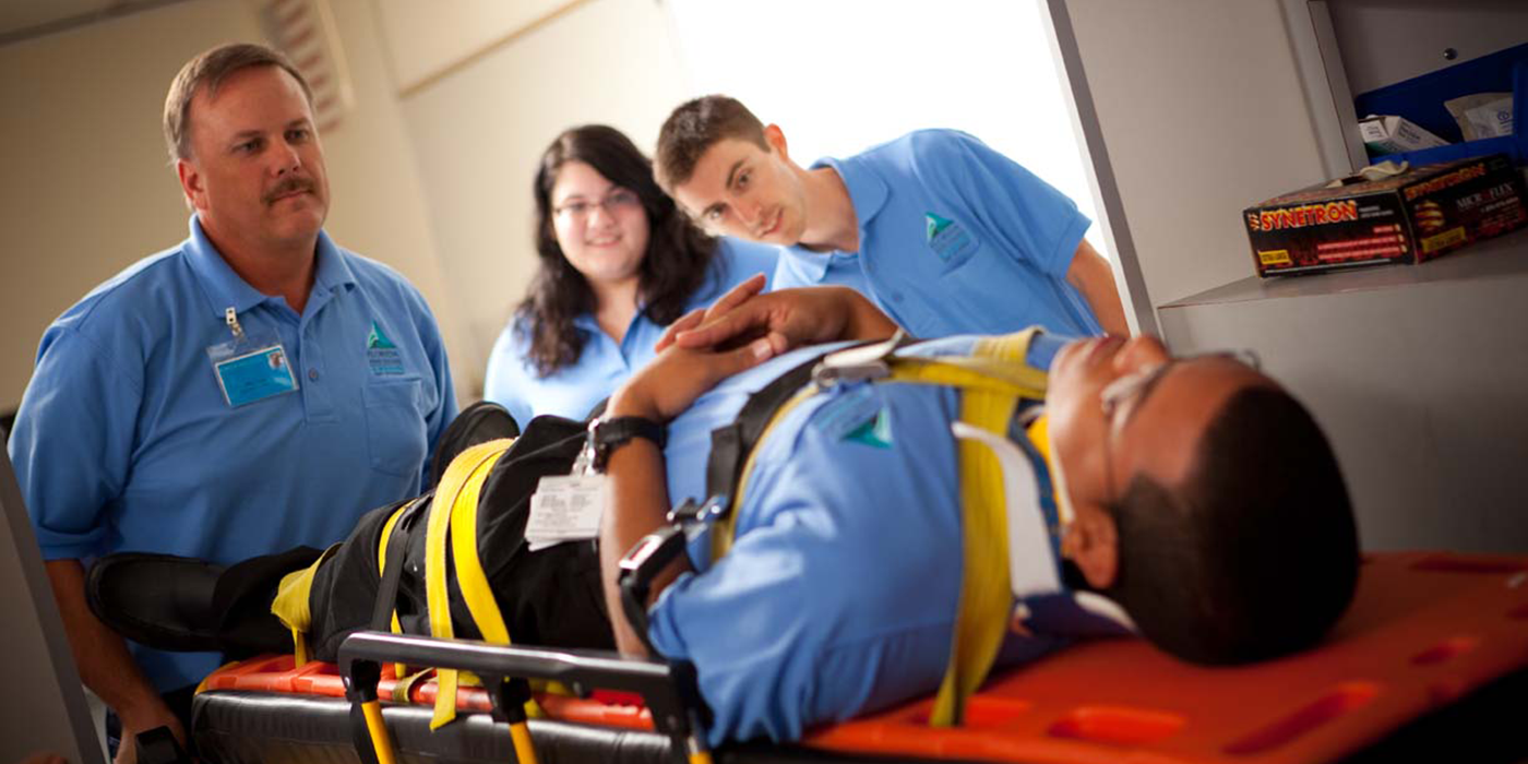 An EMT student strapped to a headboard being attended to by other EMT students