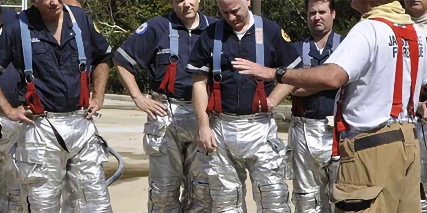 A group of firefighters dressed in partial fire gear conversing