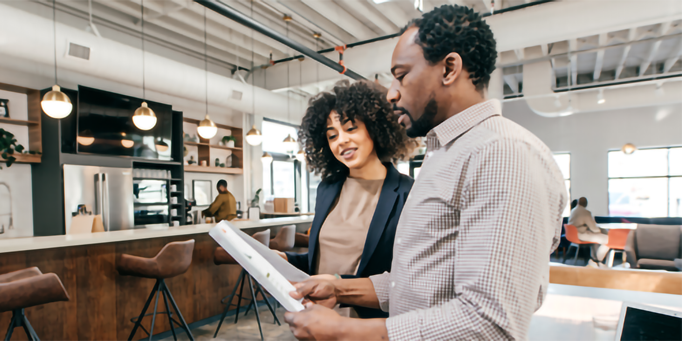 Two people discussing a paper in a coffee shop environment