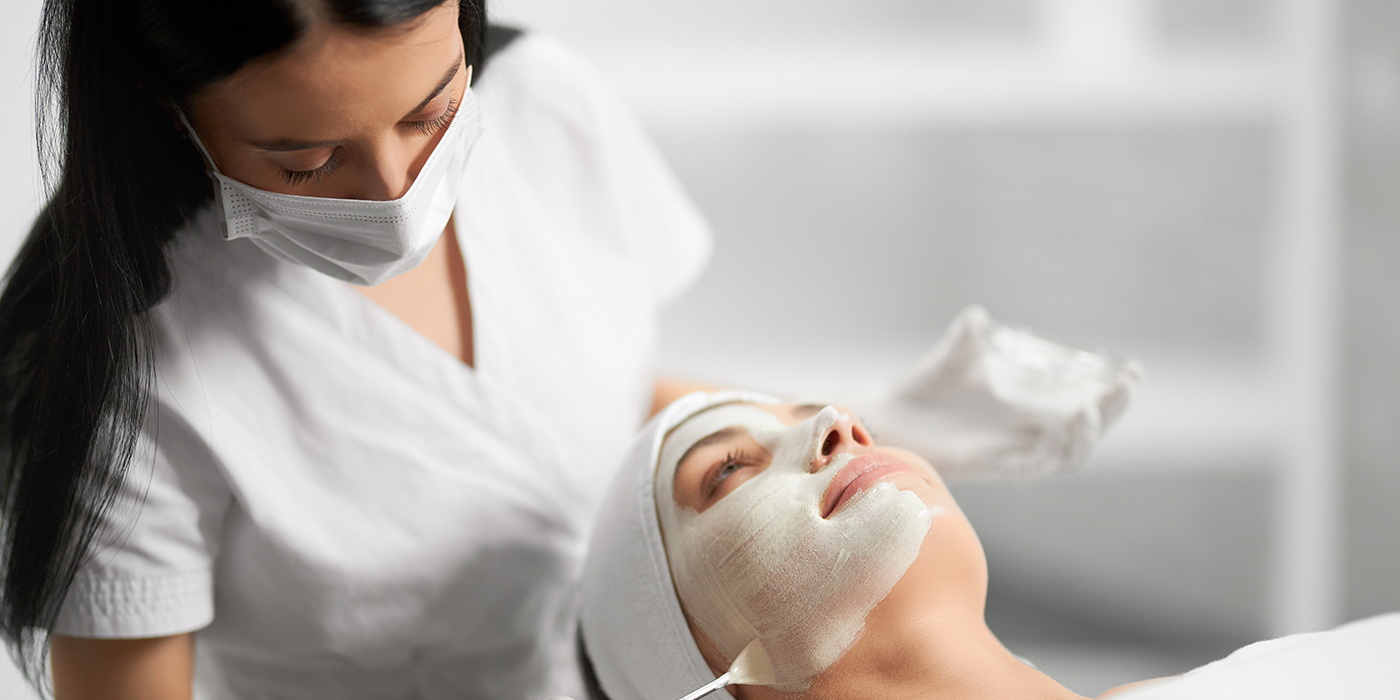 A woman applying a facial mask to another woman