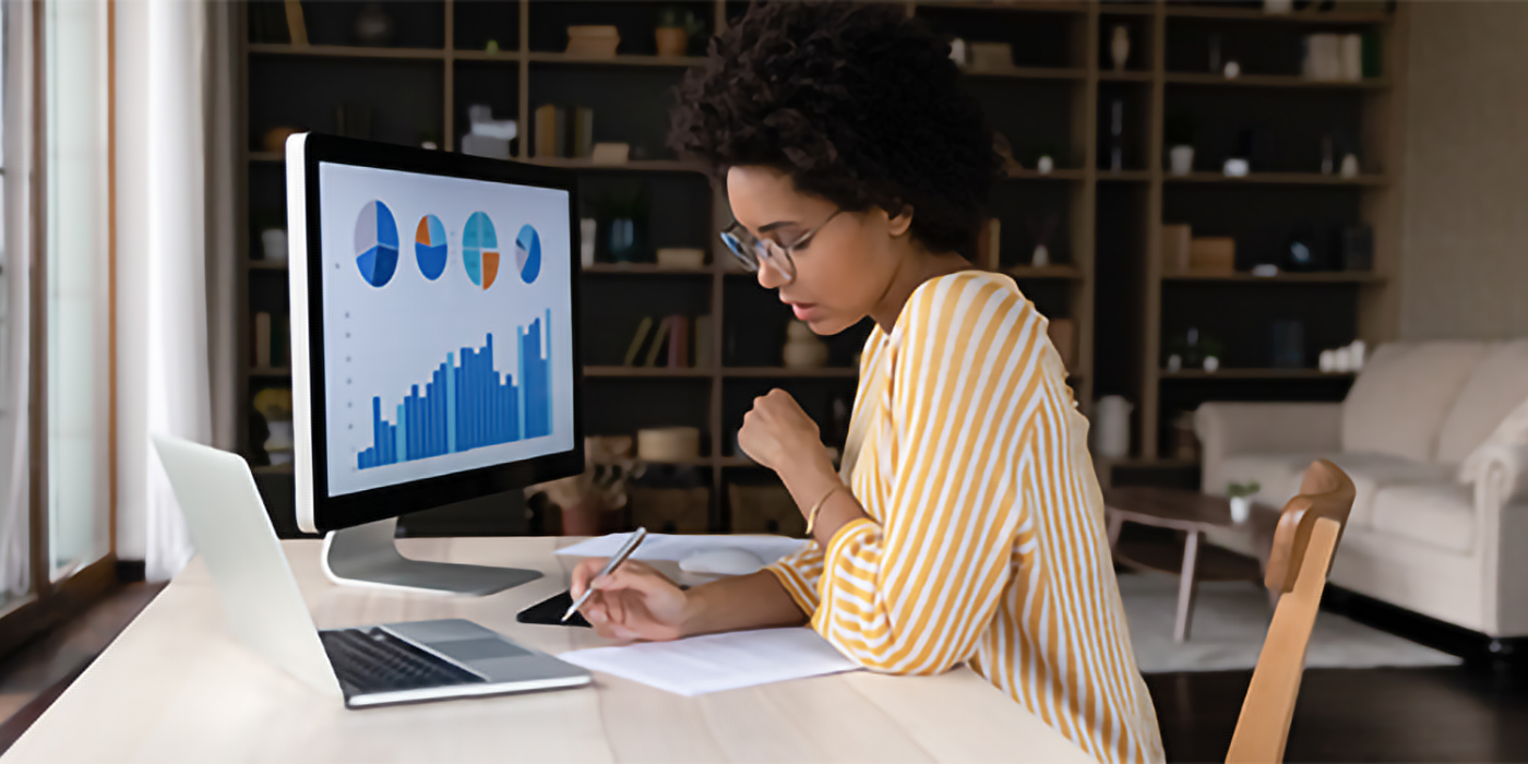 A woman using a computer with various charts on the screen