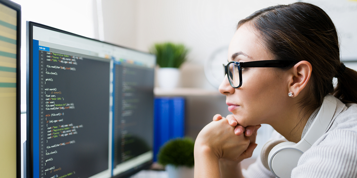 A woman looking at a computer screen with a code editor on screen