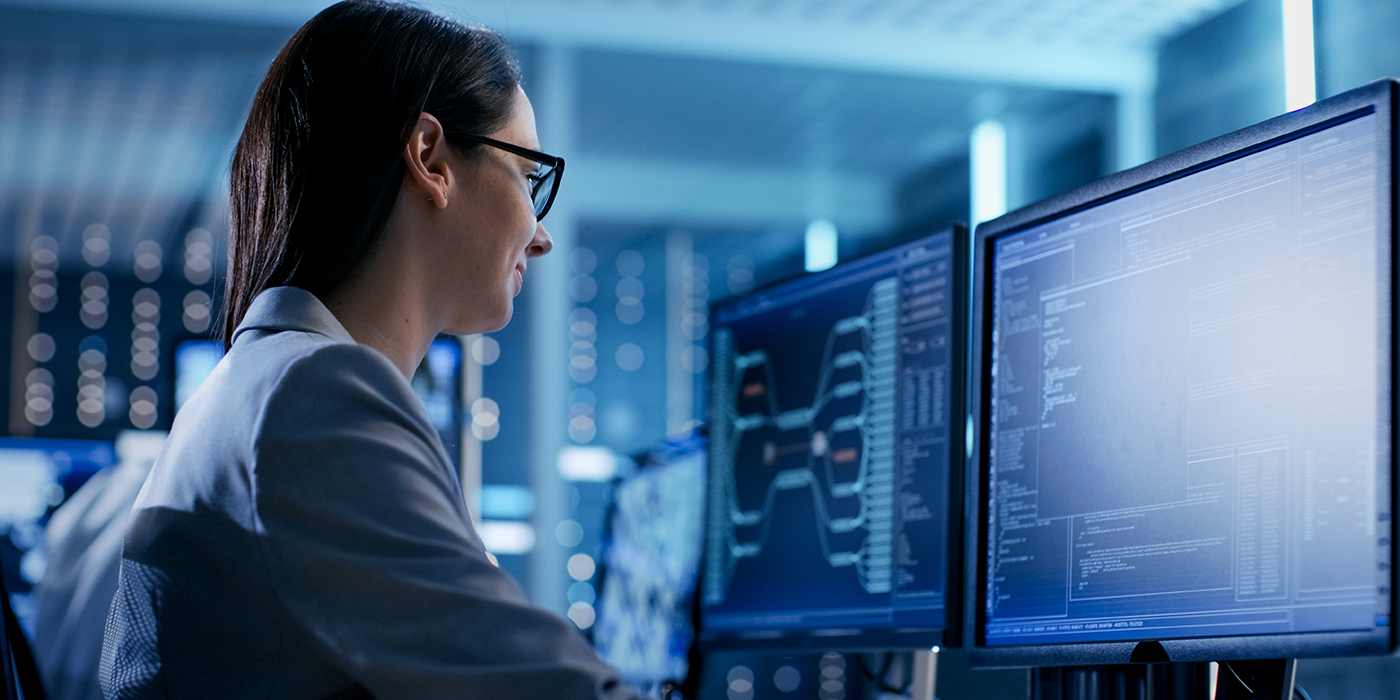 A woman using a computer with technical data on the screen.